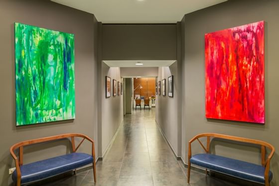 2 wall paintings & chairs in the lobby hallway at Kinzie Hotel