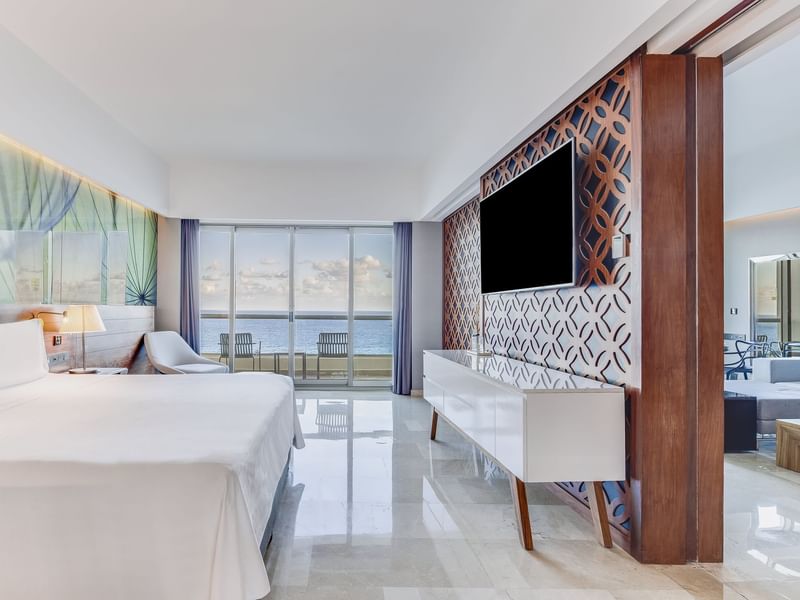 Bedroom with bed facing TV, large windows and comfy chairs at Live Aqua Cancún (Adults Only)