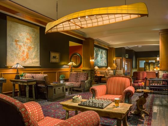 Hotel lobby lounge with comfortable chairs, a chessboard on a table, and a unique canoe light fixture at High Peaks Resort