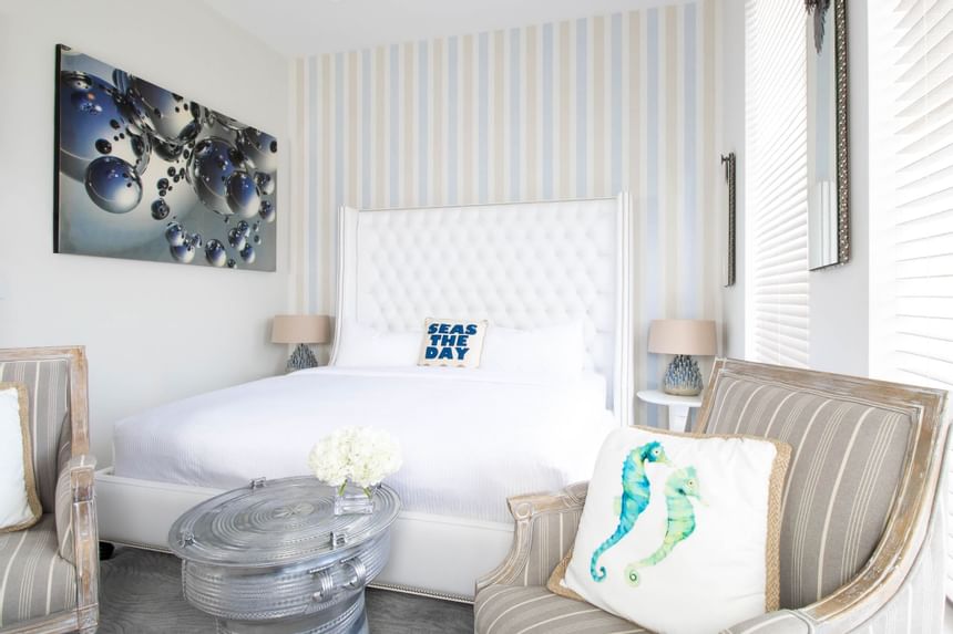 King bed with padded headboard & comfy chairs by a cozy bed in King Premiere Palm at Retro Suites Hotel