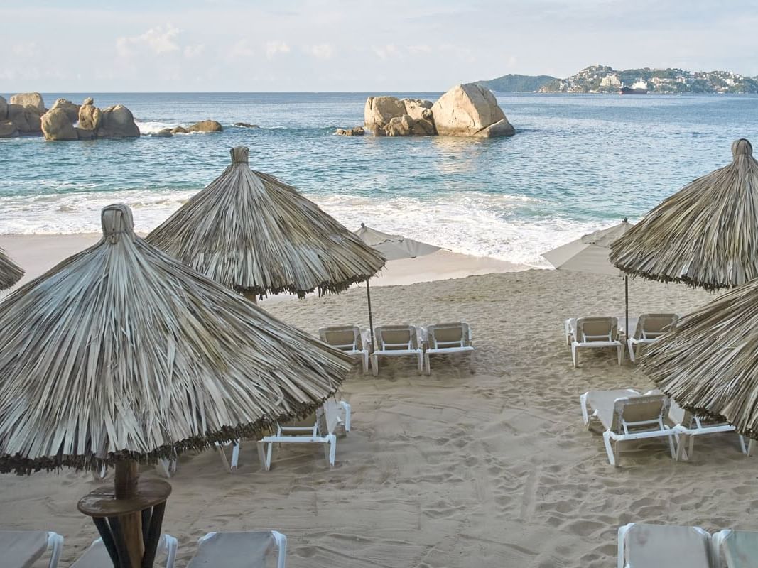 Umbrellas & deck chairs on a beach in Acapulco at La Colección