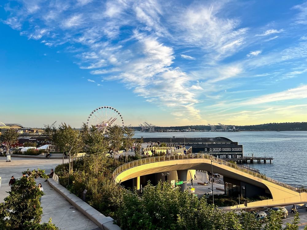 Ferris wheel by a stone path and greenery overlooking the ocean bay, near Warwick Seattle