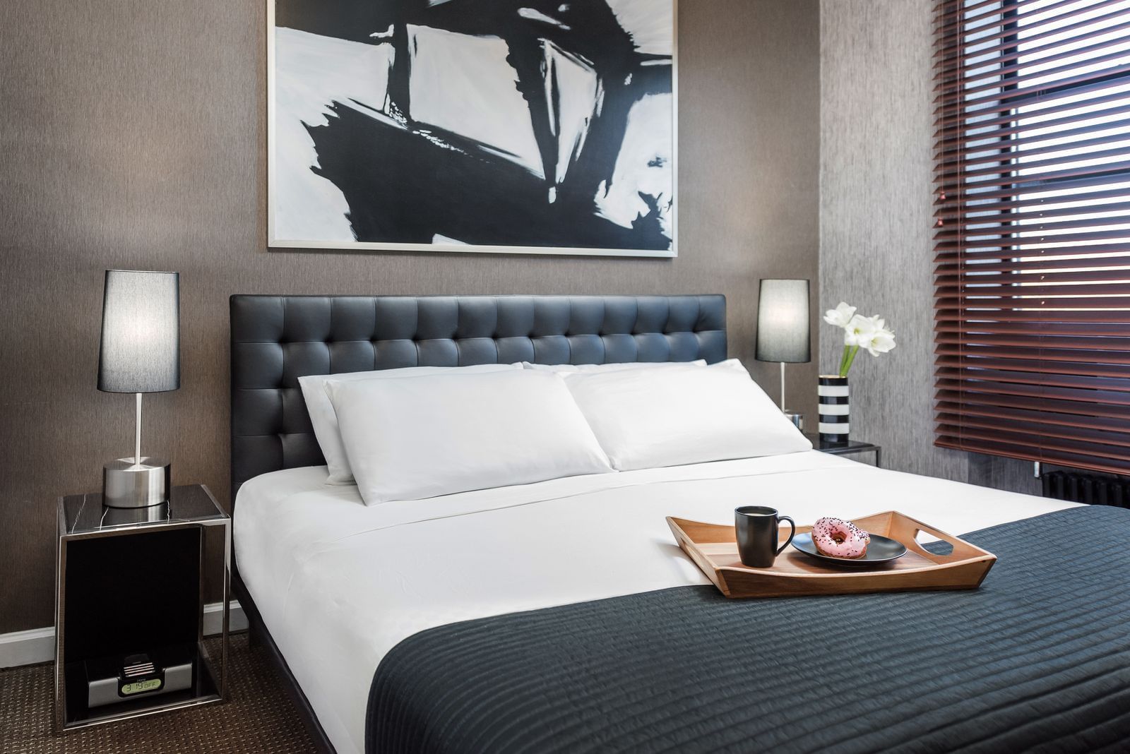 a tray on a bed with coffee and a donut