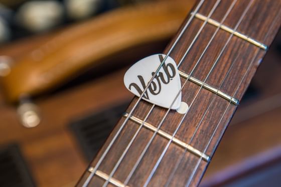 Guitar neck detail shot with Verb branded guitar pick at The Verb Hotel