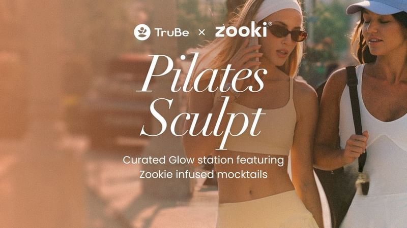 Deux femmes en tenue de sport se promenant en plein air, arborant bien en évidence le logo de l'événement « Pilates Sculpt » ainsi que les logos du partenariat avec Zooki.