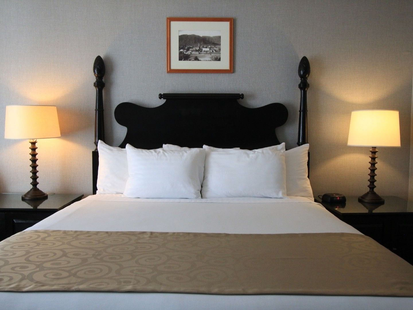 Deluxe 1 King room with dark wood bed, white linens, bedside lamps, and framed artwork at Polynesian Residences, Honolulu