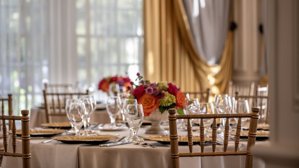 Elegantly set dining table with floral centerpieces in Crystal Ballroom at Warwick Melrose Dallas.