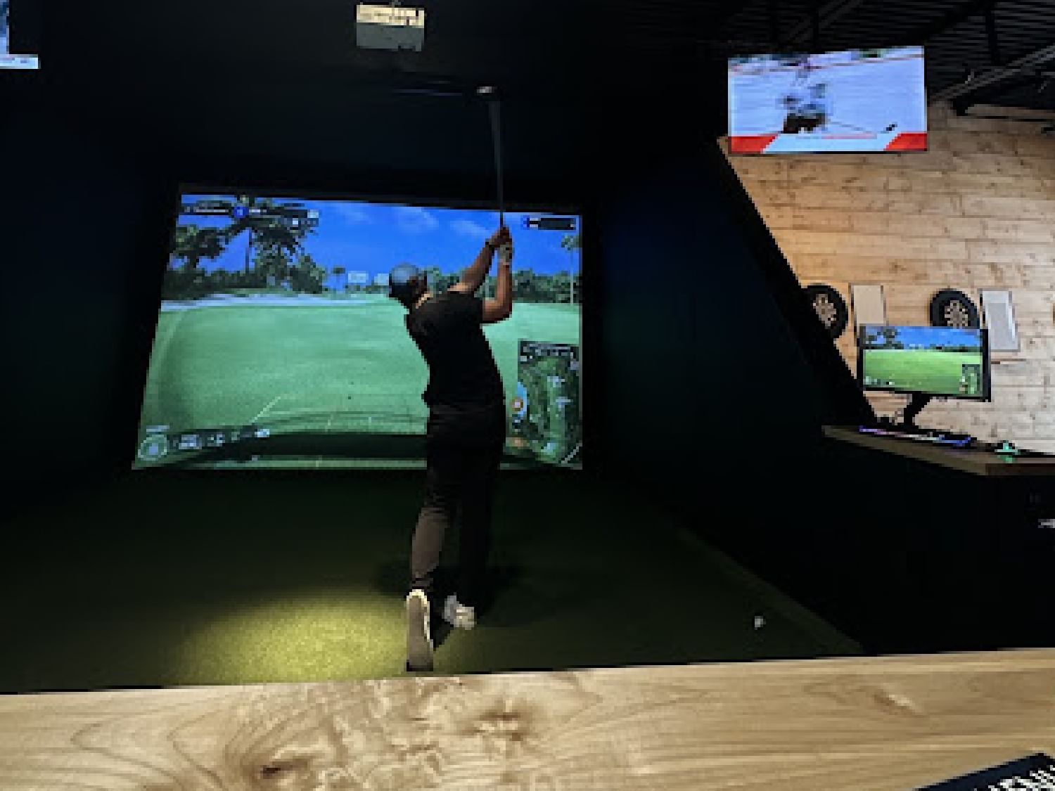 Man playing simulation golf with a digital screen in Par 72 Golf Lounge near Retro Suites Hotel