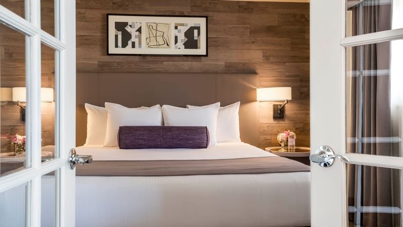Cozy bed with side tables and wall art in Premiere Suite at Warwick Denver