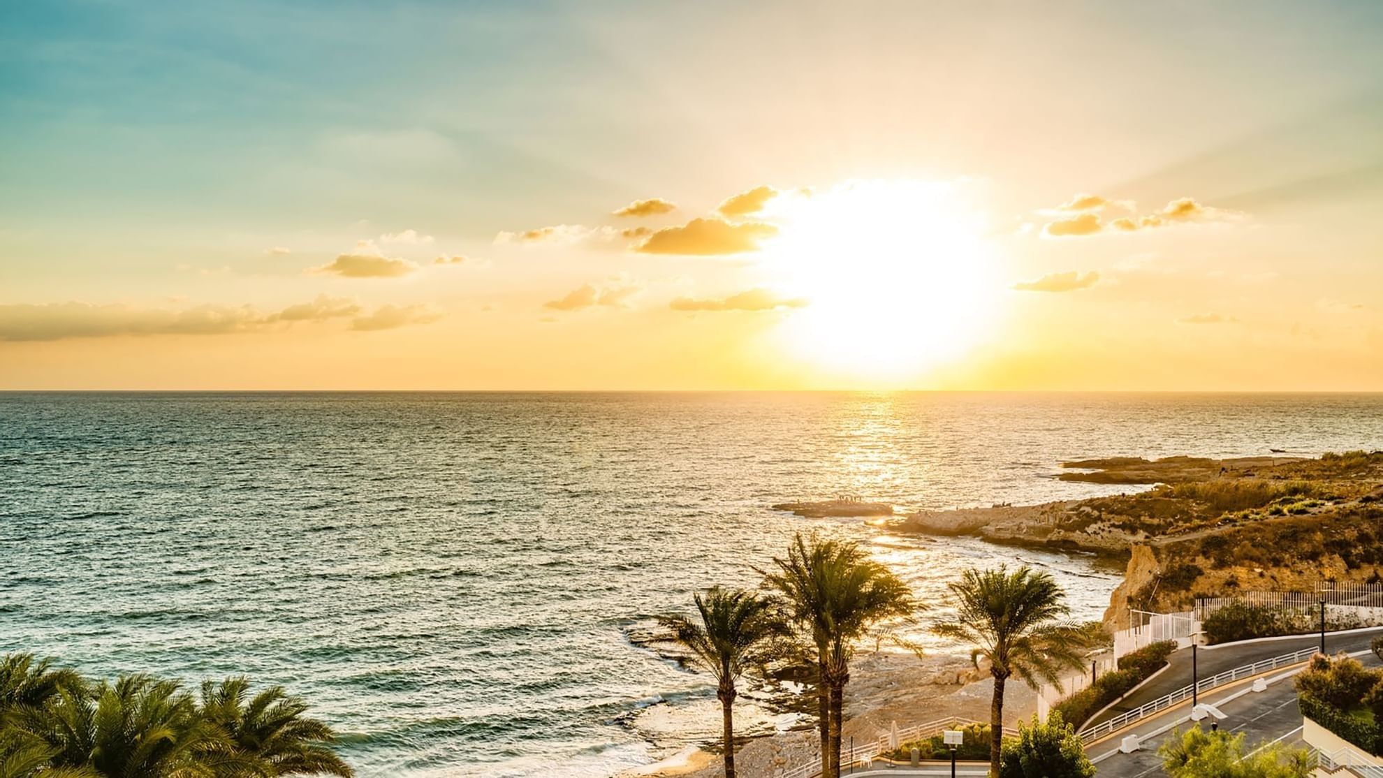 Sun setting over the ocean under a golden sky along the coast near Warwick Palm Beach Hotel