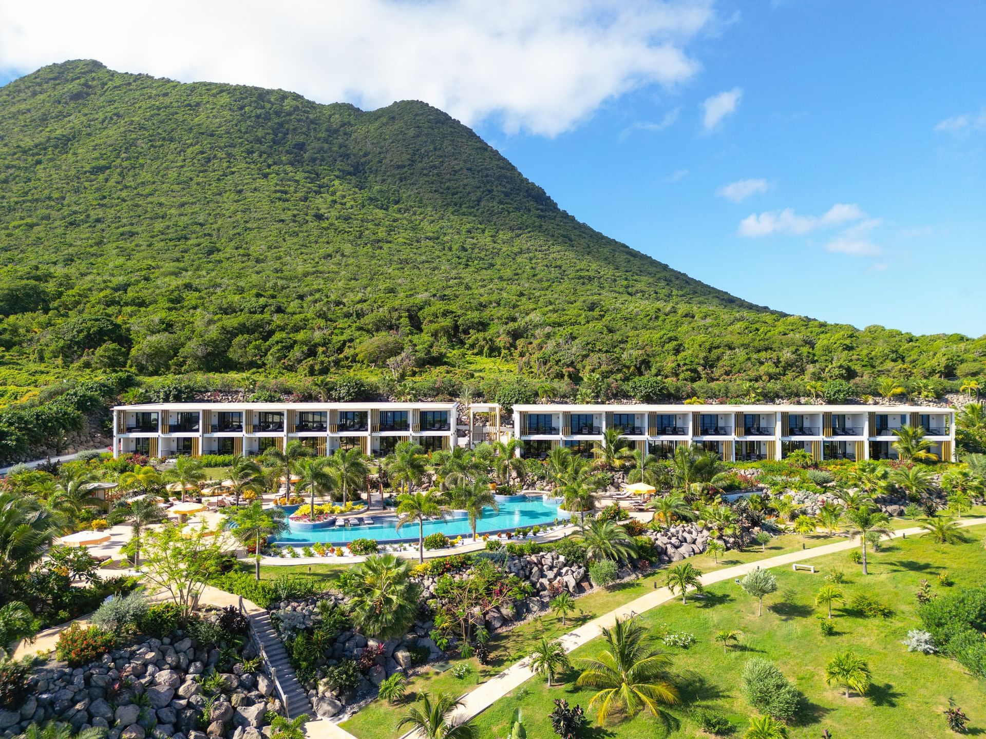 Exterior view of Golden Rock Resort with an outdoor pool, surrounded by lush greenery and a mountainous backdrop