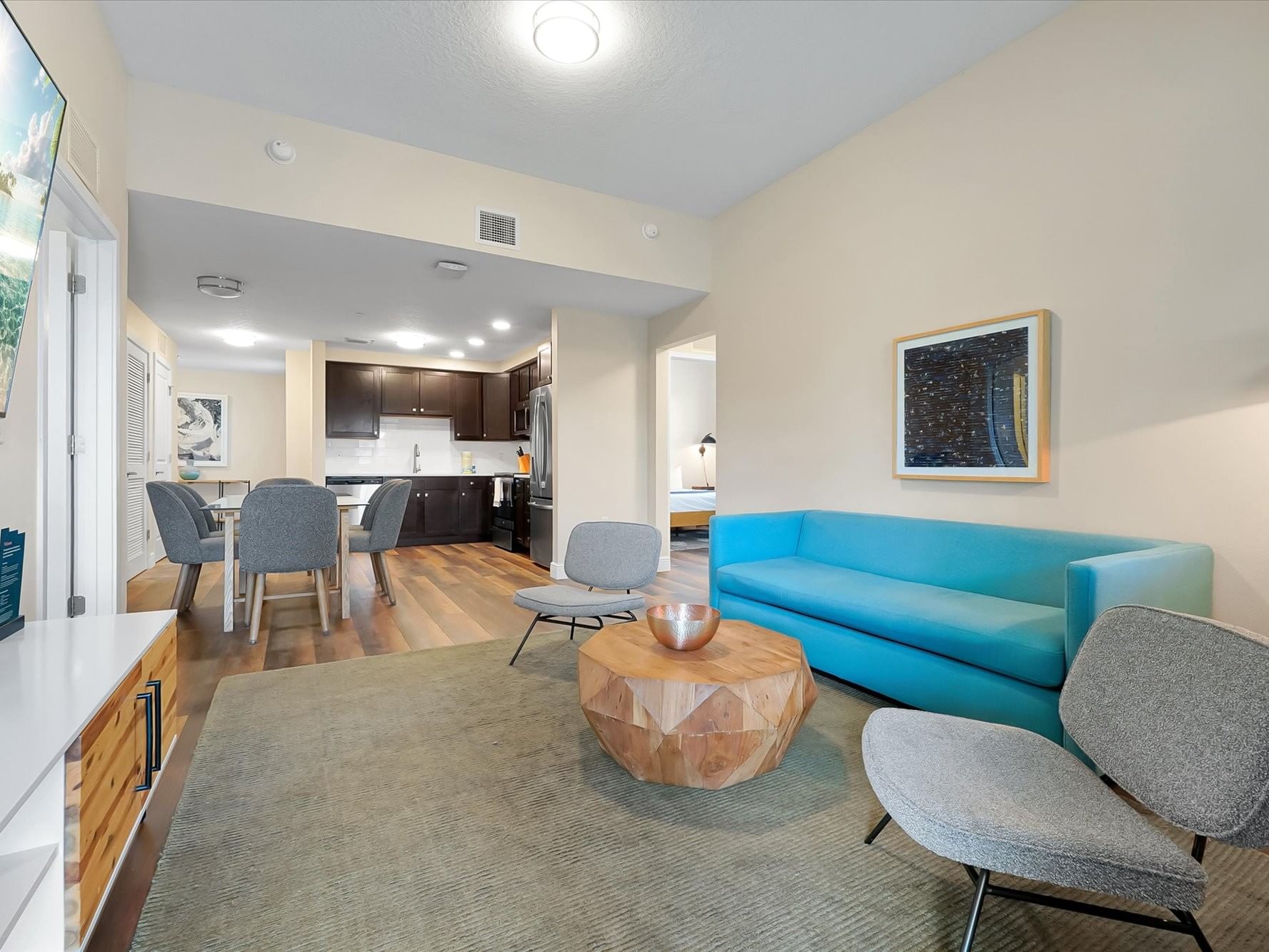 Open-plan living area with turquoise sofa, dining table, and modern kitchen at Vista Cay Resort By Millenium, Orlando.