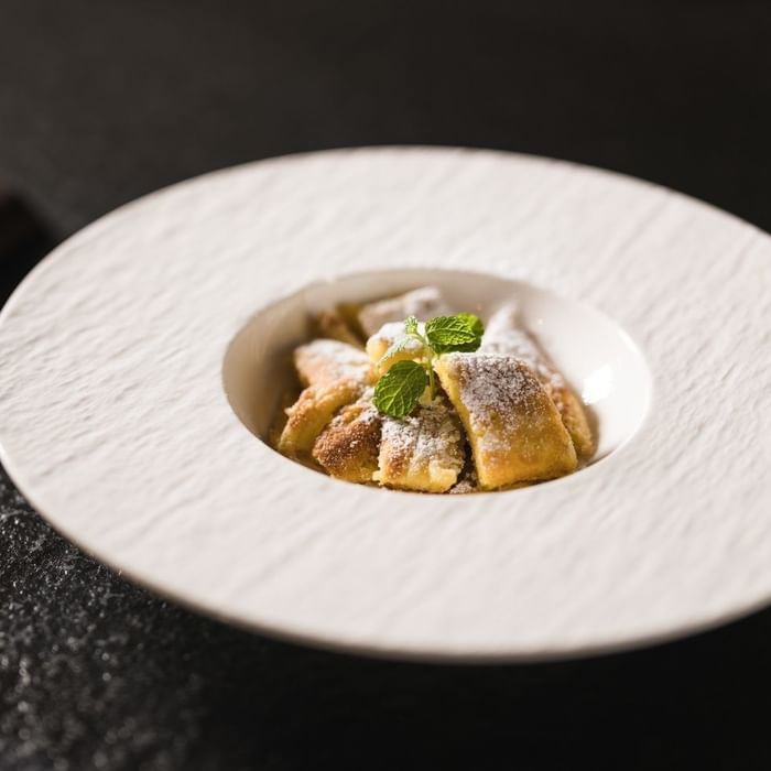 Plate of powdered pastries with mint garnish at Falkensteiner Hotel Falkensteinerhof