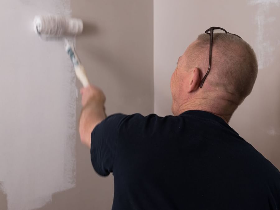 A man color washing a wall in white at Hotel Cassitel