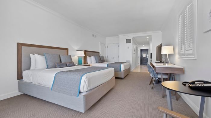 Two beds with blue runners facing work desk & lamp in One Bedroom Oceanview Suite 2 Queens at The Atlantic Hotel & Spa