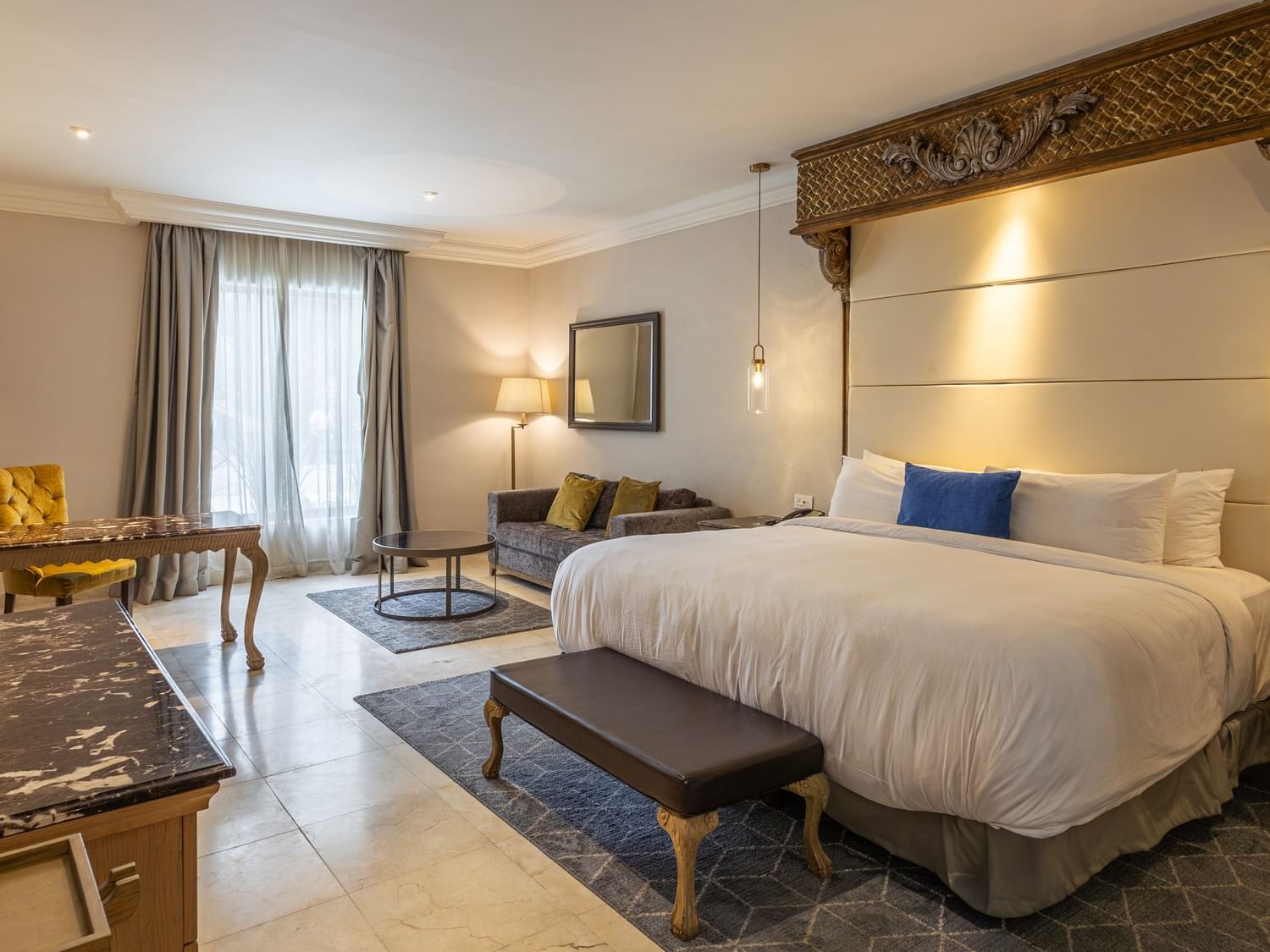 Spacious King Grand Class Plus Suite with elegant furnishings and ornate headboard at Quinta Real Monterrey.