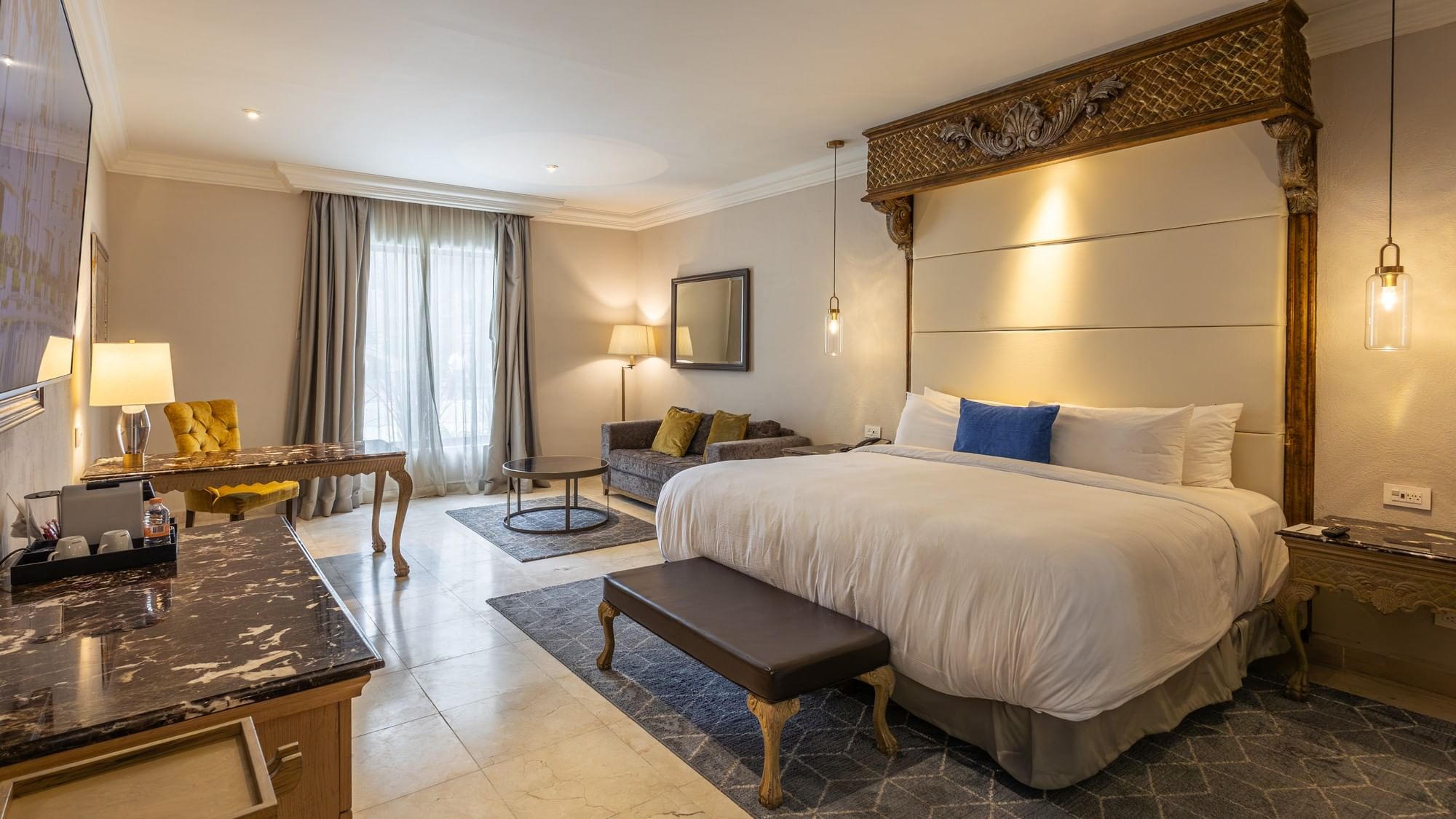 Spacious King Grand Class Plus Suite with elegant furnishings and ornate headboard at Quinta Real Monterrey.