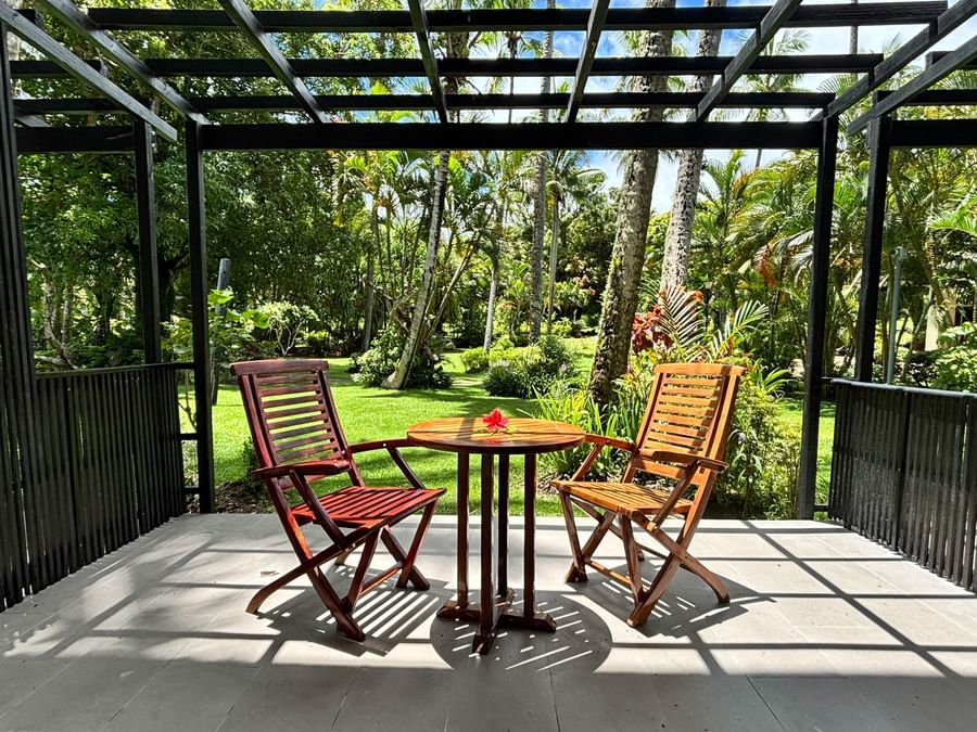 Two wooden chairs and table on a patio with lush greenery at Warwick Fiji Resort and Spa.