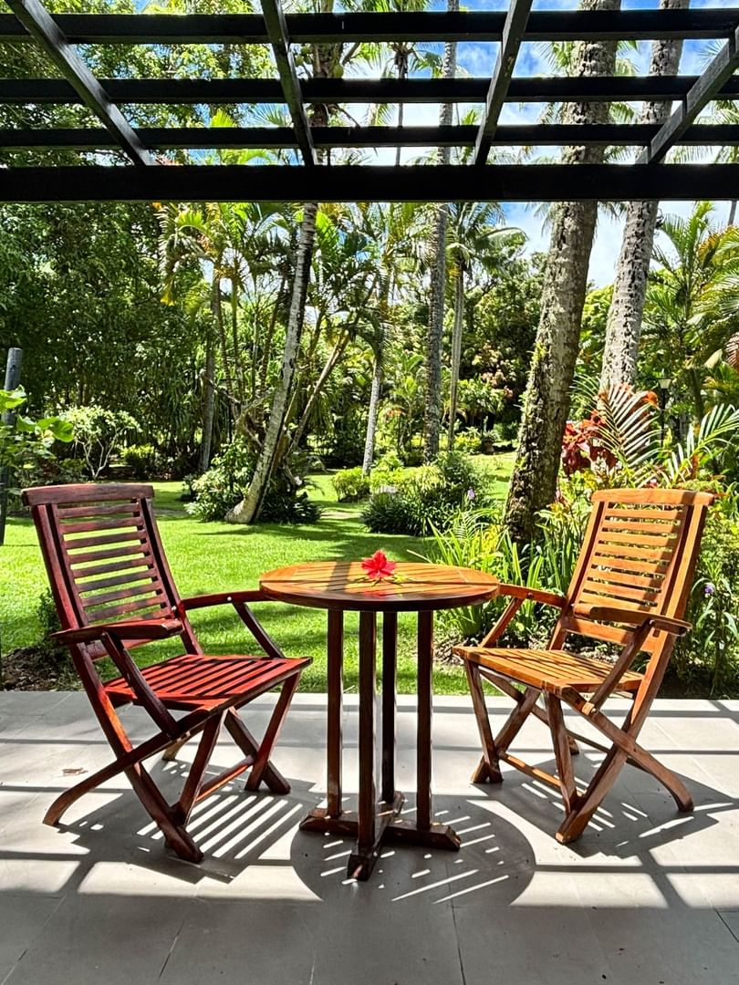 Wooden patio with chairs and table overlooking lush garden at Warwick Fiji Resort and Spa, Korolevu.