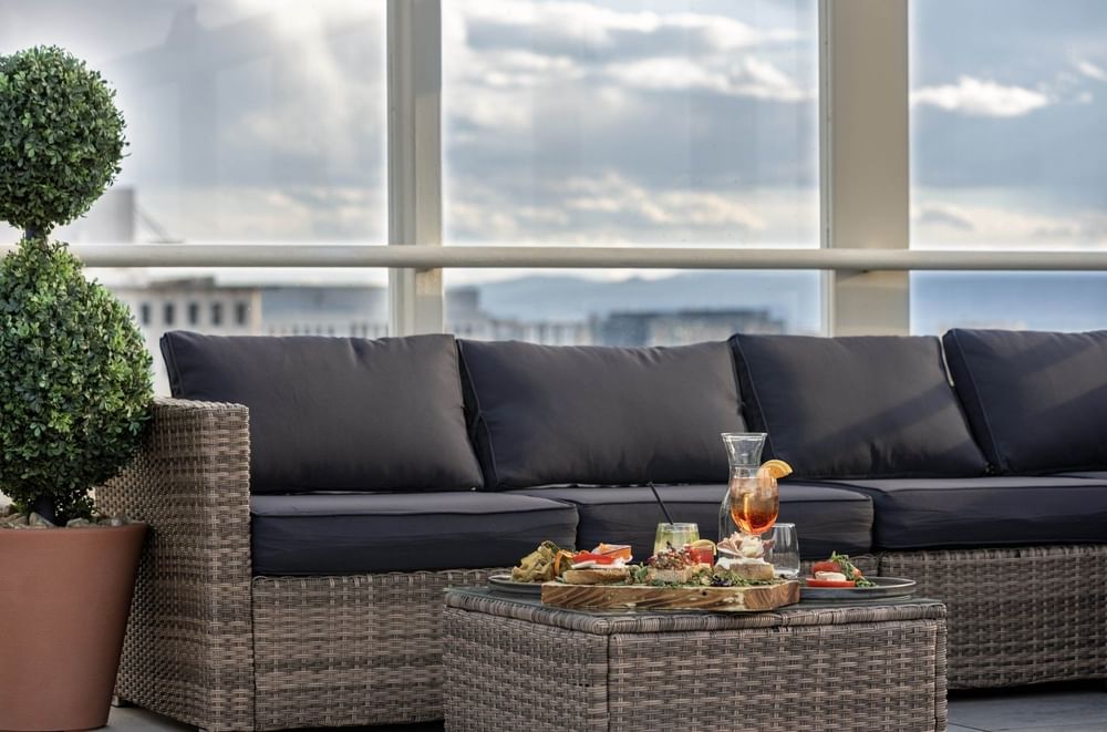 Wicker sofa by a table under a cloudy sky near glass railings at Warwick Denver