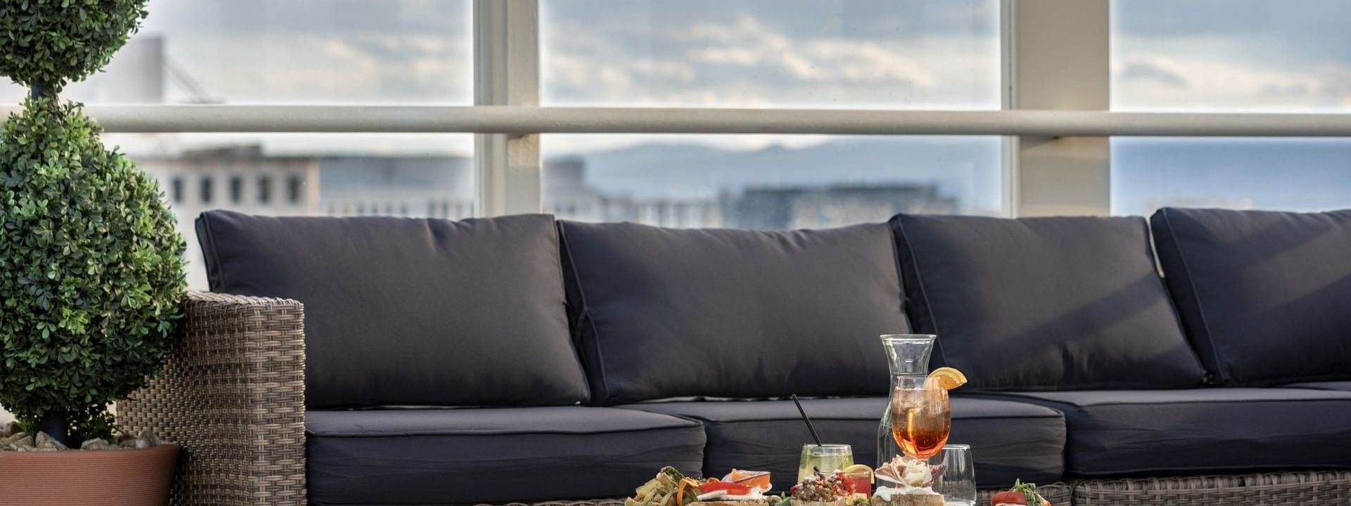Wicker sofa by a table under a cloudy sky near glass railings at Warwick Denver