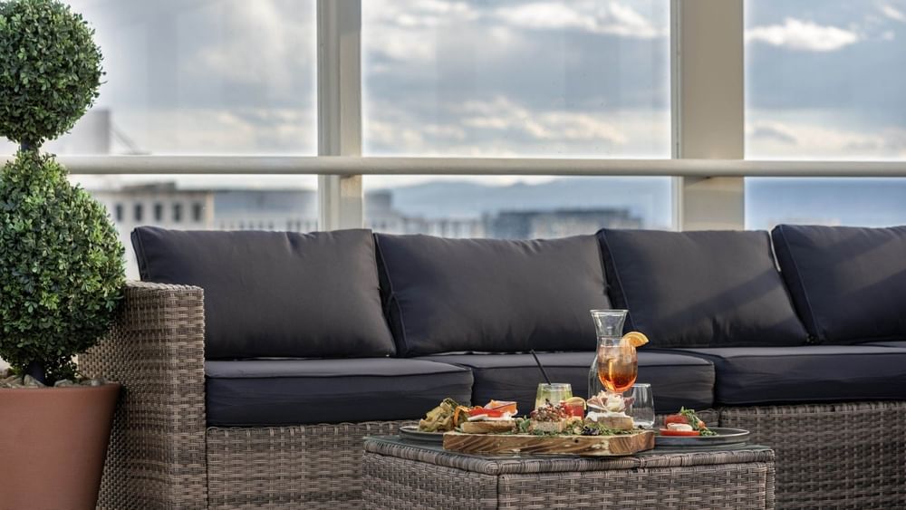 Wicker sofa by a table under a cloudy sky near glass railings at Warwick Denver