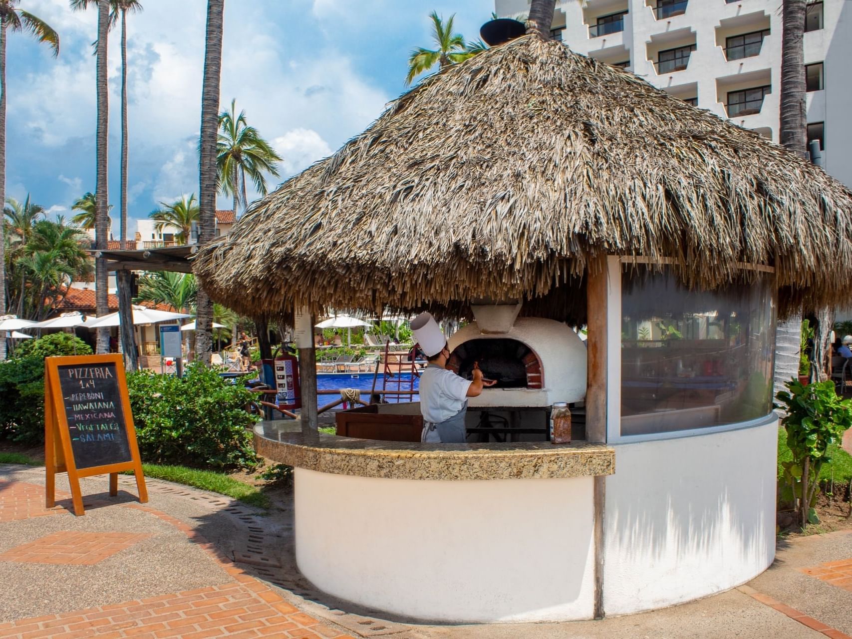 Exterior view of Pizzeria with thatched roof at Plaza Pelicanos Grand Beach Resort