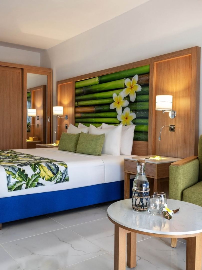 Large bed beside cozy green armchair with tropical decor in Garden View Room at warwick le lagon-vanuatu