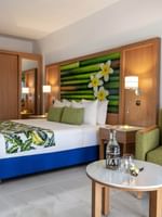 Large bed beside cozy green armchair with tropical decor in Garden View Room at warwick le lagon-vanuatu