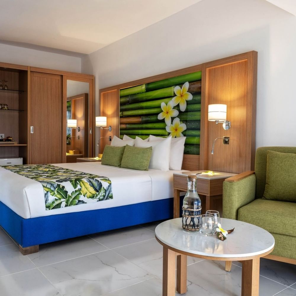 Large bed beside cozy green armchair with tropical decor in Garden View Room at warwick le lagon-vanuatu