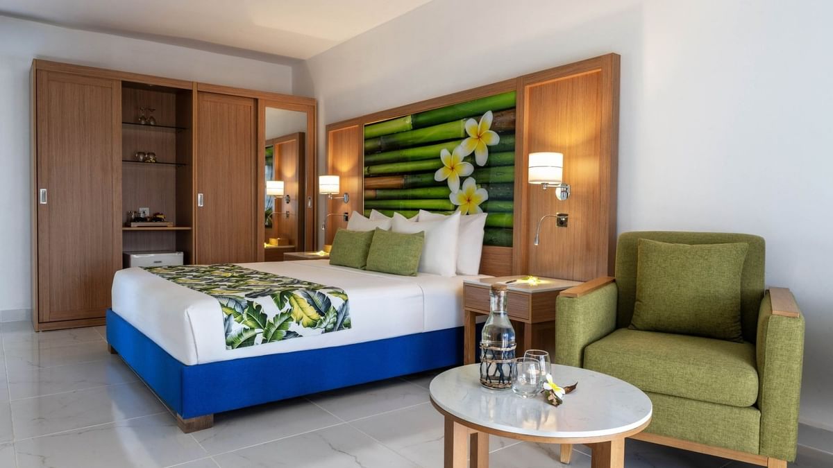 Large bed beside cozy green armchair with tropical decor in Garden View Room at warwick le lagon-vanuatu