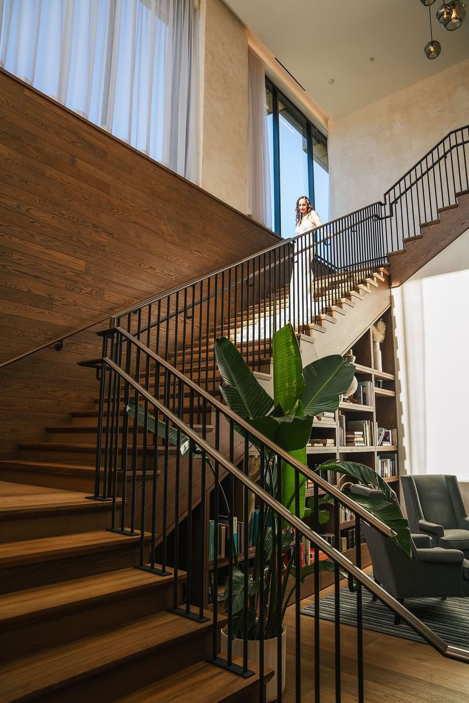 Woman in a wedding dress descending a sunlit wooden staircase in The Study at University of Chicago