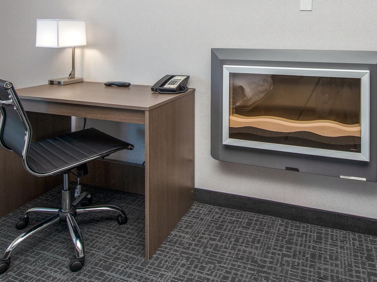 Desk with lamp, phone, and modern fireplace.