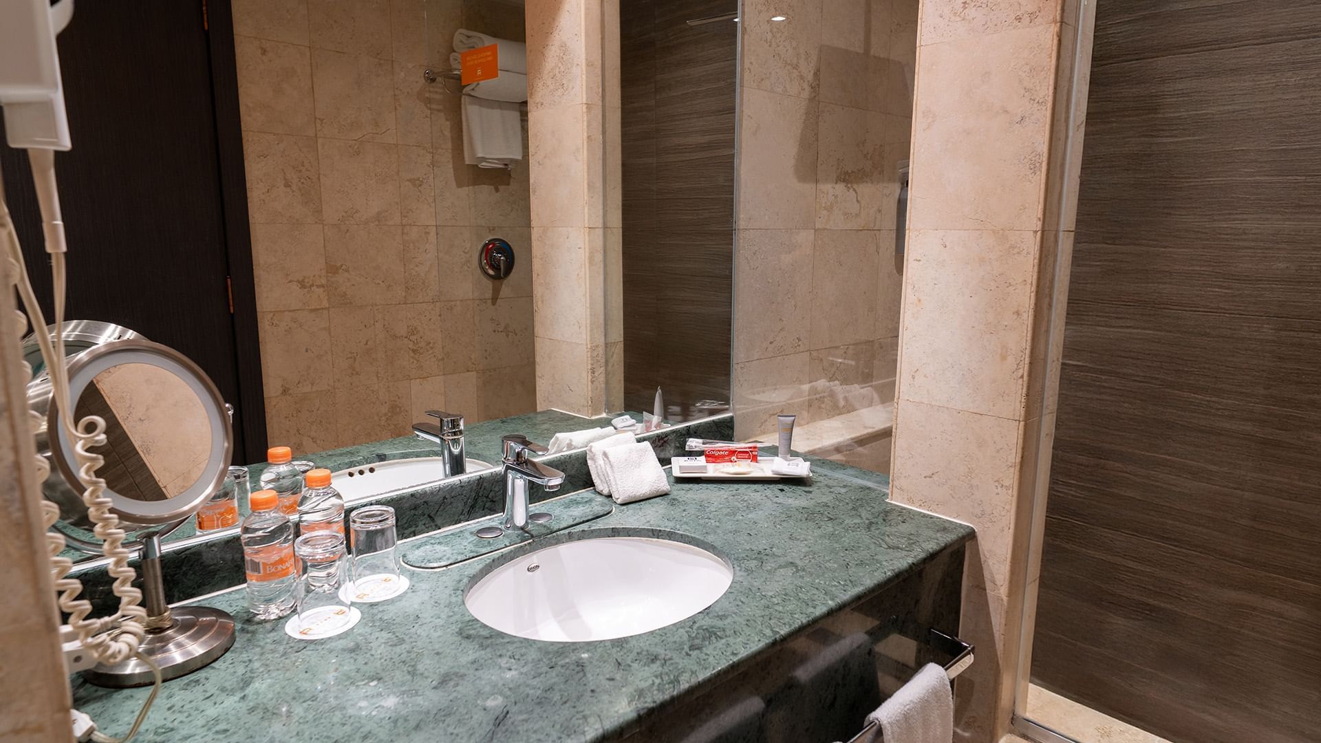 Bathroom with a green marble vanity, large mirror, and bottled water in the Two Double Master Suite at Real Inn Tijuana
