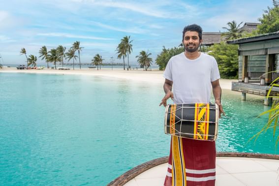 Man playing a drum on a tropical beach deck at Grand Park Kodhipparu, Maldives