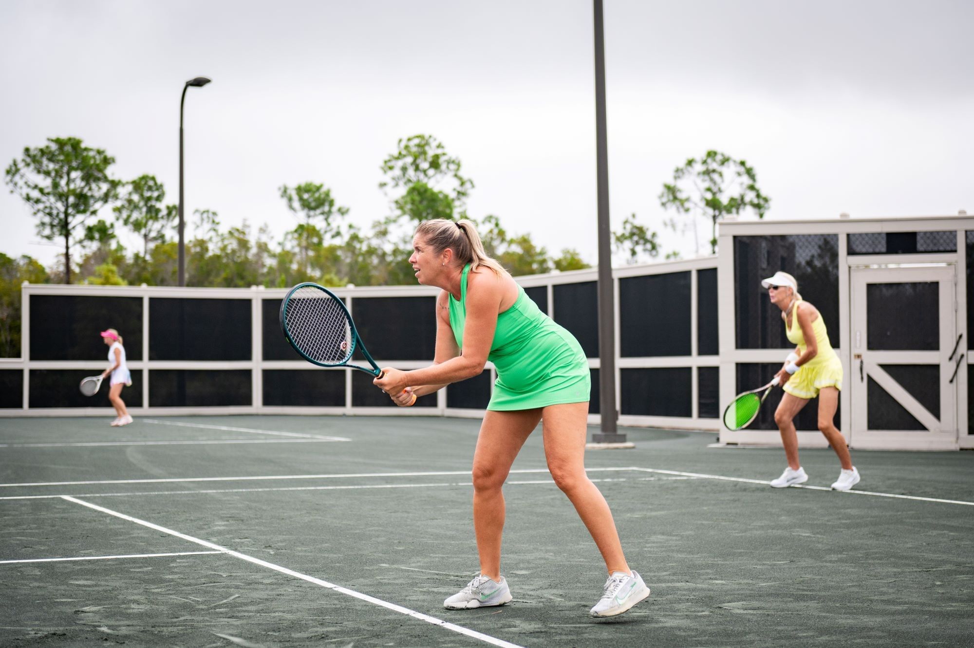 A woman playing tennis holds her racquet up preparing to return a serve