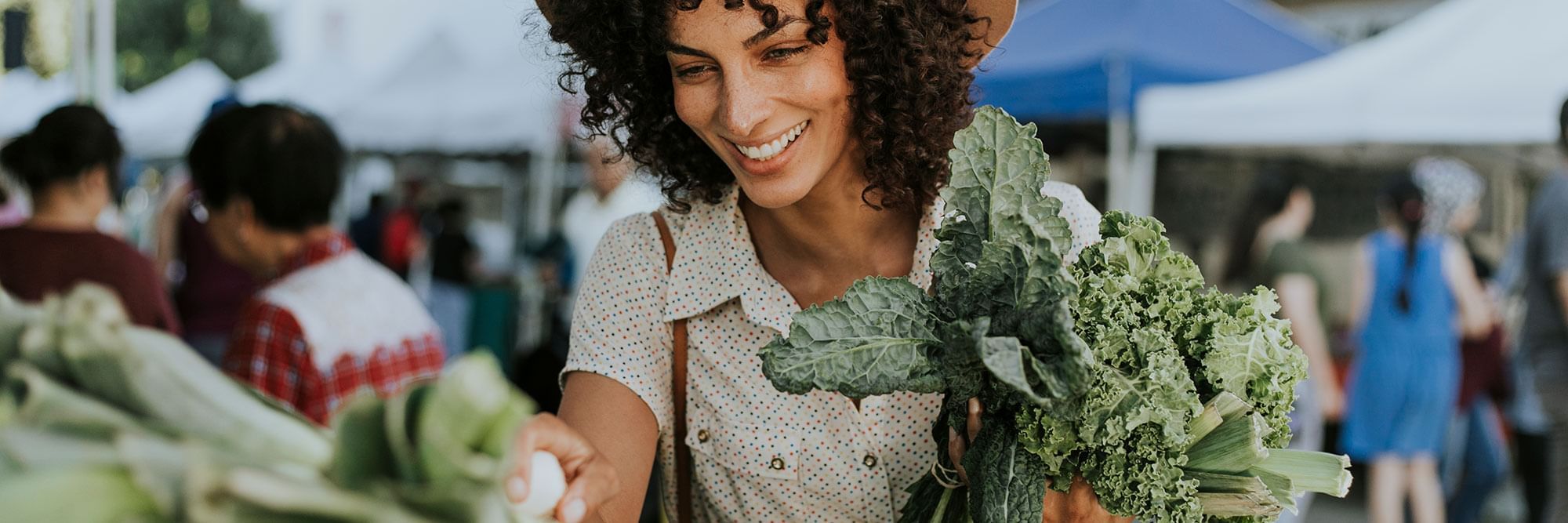 Woman holding produce at farmers market.