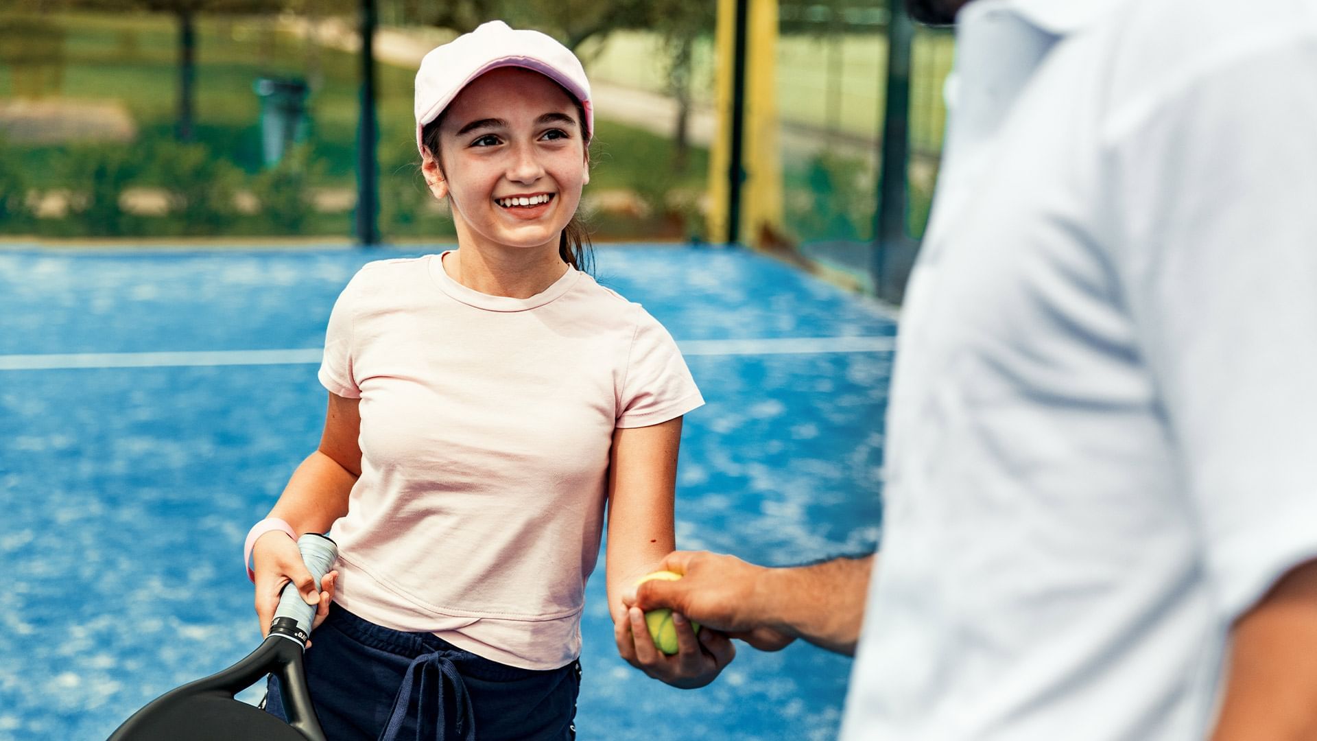 Eine Frau in Sportkleidung hält einen Tennisschläger und erhält eine Lektion von einem Trainer.