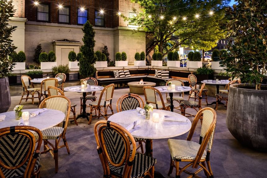 Dining area with wooden tables and woven chairs in The Garden at Hotel Sorrento