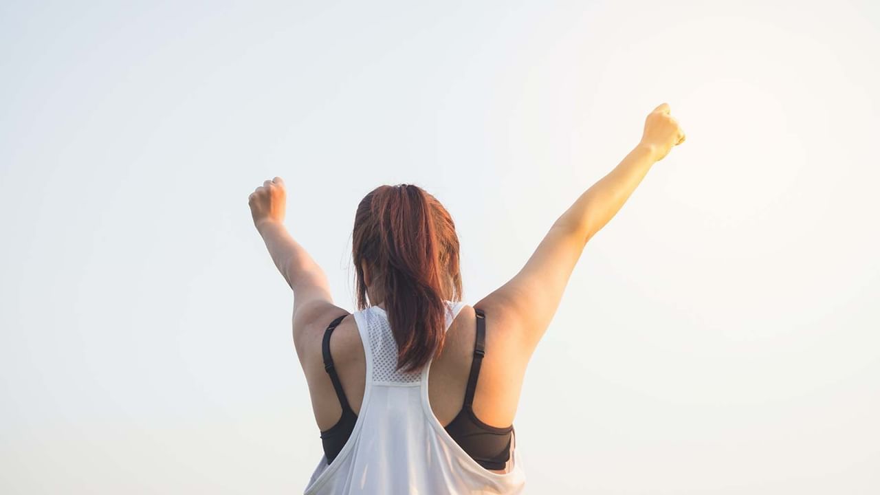 Back of woman in fitness clothes cheering with arms in air