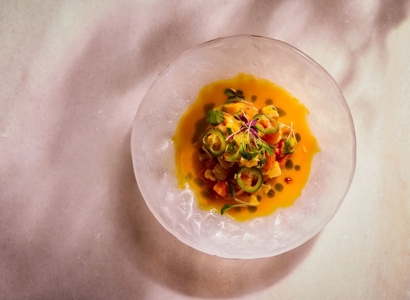 Colorful dish with vegetables, sauce, and garnish in a clear bowl at The Londoner