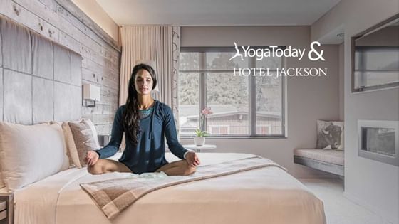 Lady doing yoga on a bed at Hotel Jackson