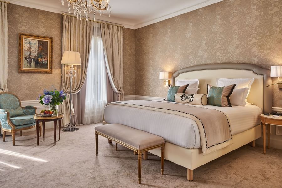 Bed with ottoman and couch near the window in Prestige Suite at Hotel Westminster Paris