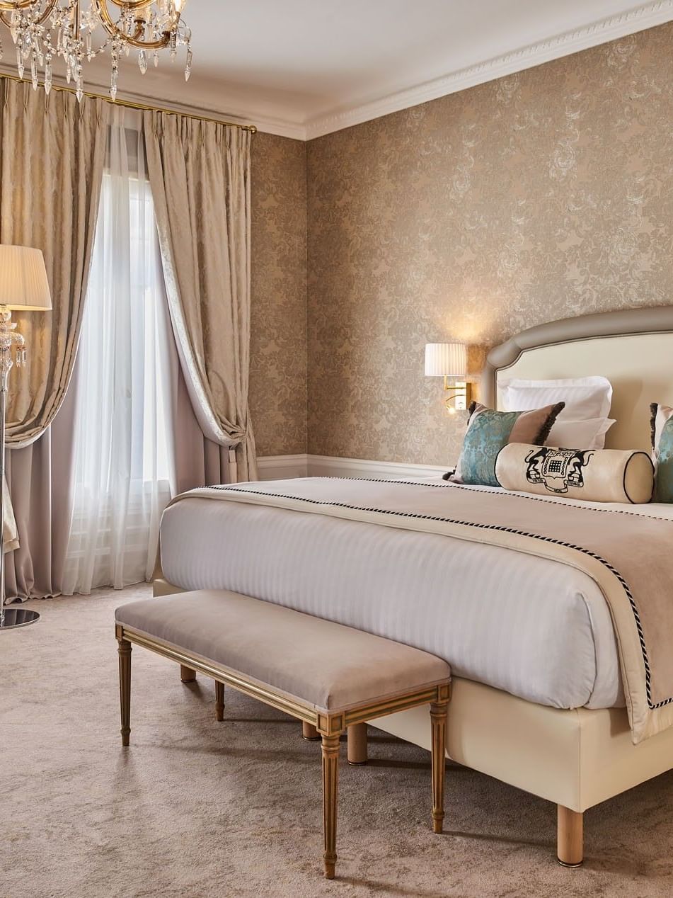 Bed with ottoman and couch near the window in Prestige Suite at Hotel Westminster Paris