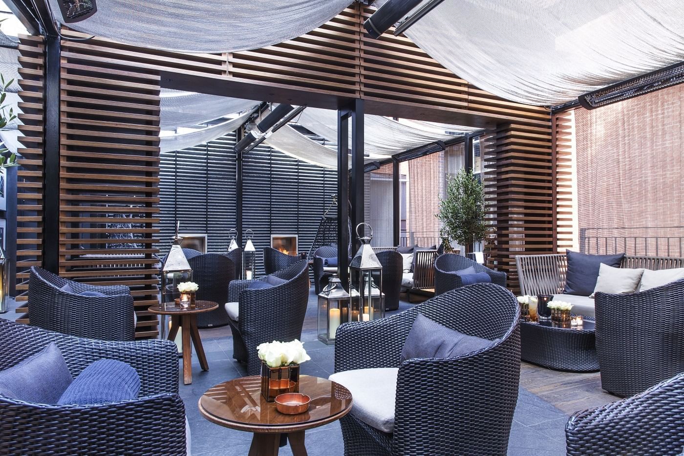 Elegant outdoor seating area with wicker chairs and tables at The May Fair Hotel, London.