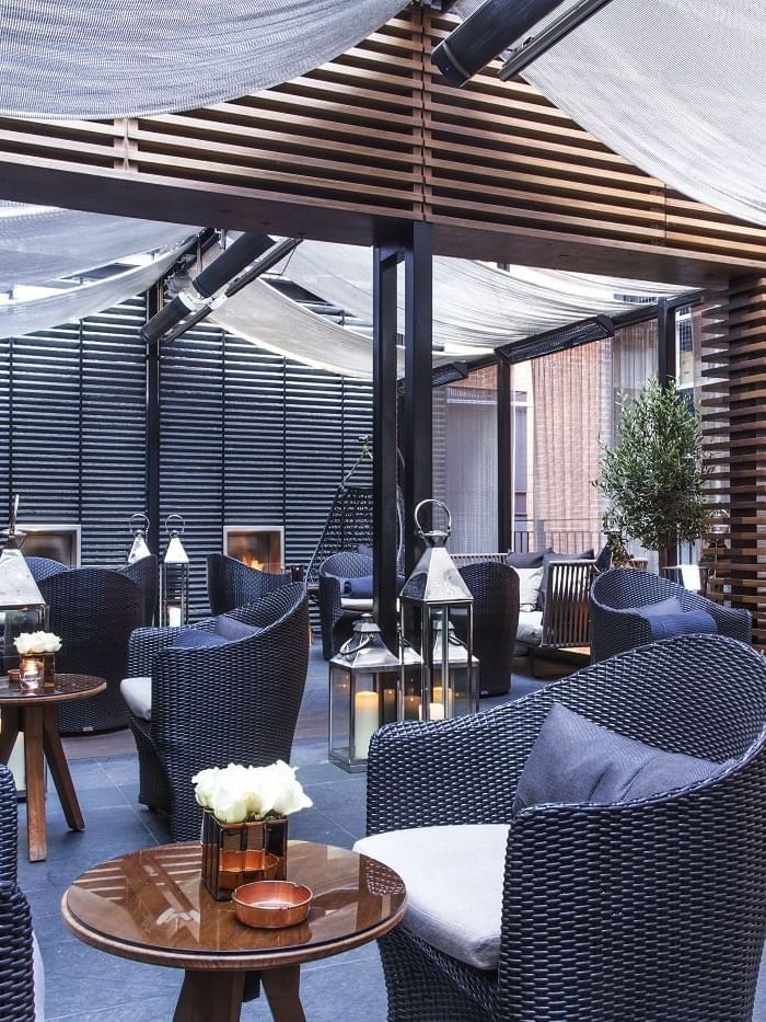Elegant outdoor seating area with wicker chairs and tables at The May Fair Hotel, London.
