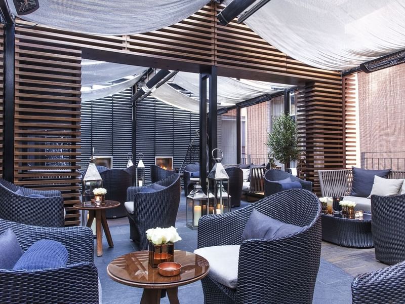 Elegant outdoor seating area with wicker chairs and tables at The May Fair Hotel, London.