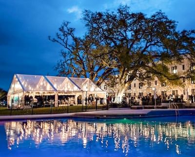 An evening outdoor event under a lit tent by a pool at dusk inside The White House Hotel
