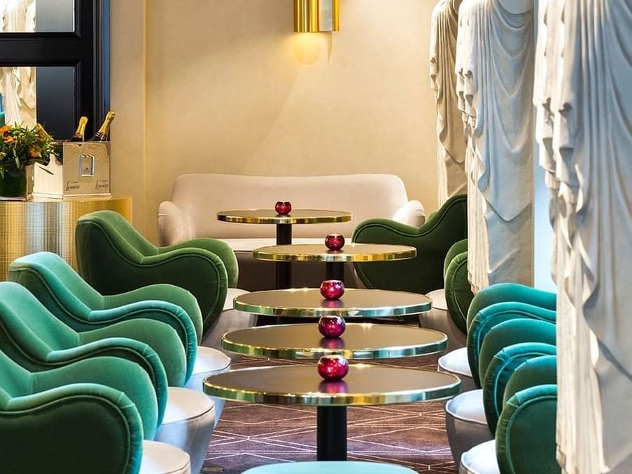 Green velvet armchairs and gold-rimmed tables in the chic lounge at Hotel Barsey by Warwick