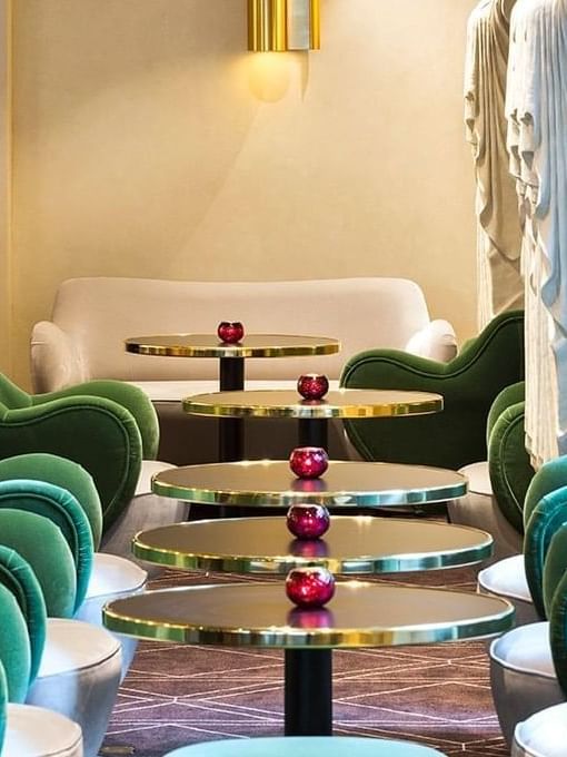 Green velvet armchairs and gold-rimmed tables in the chic lounge at Hotel Barsey by Warwick
